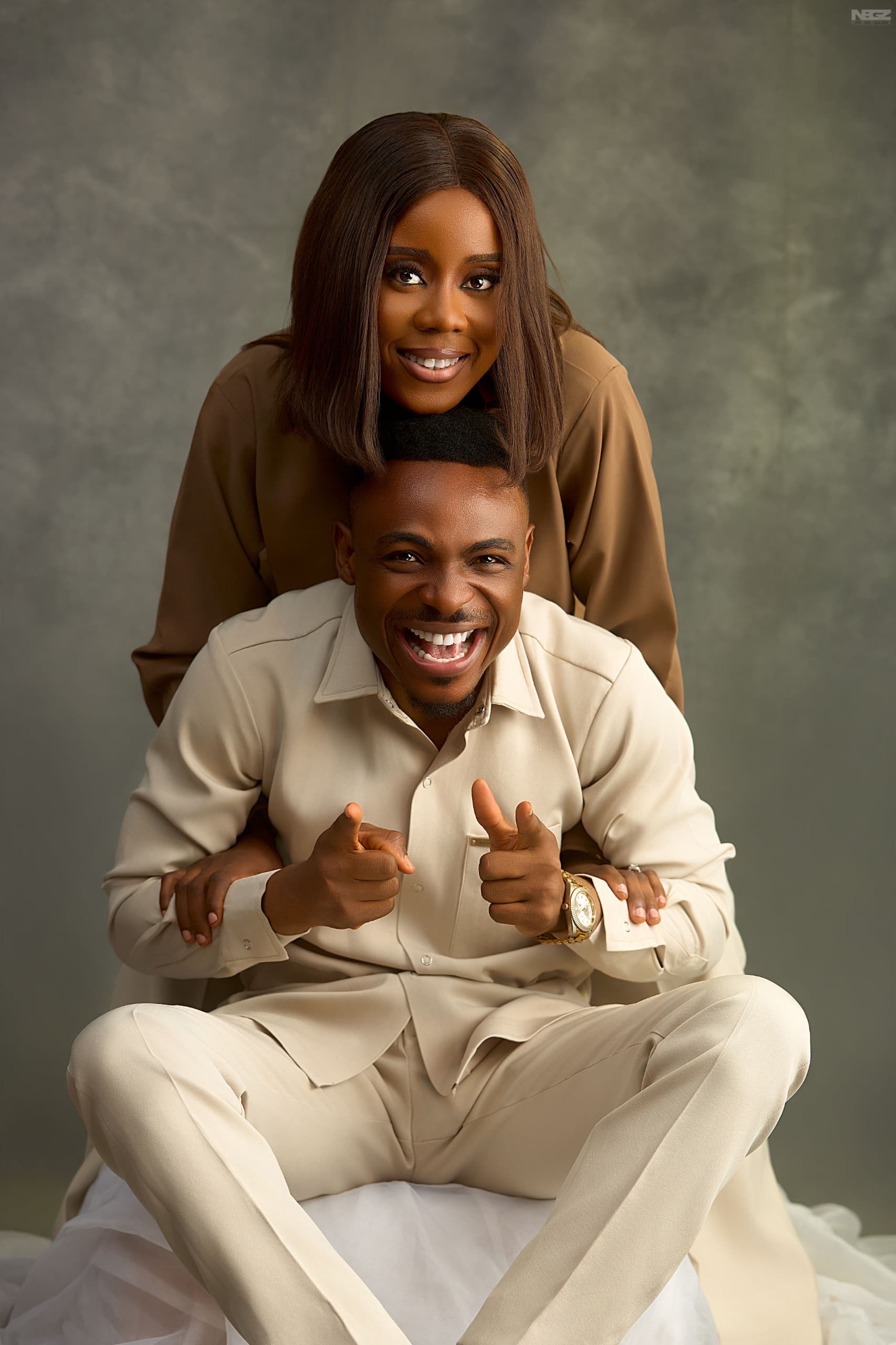 James Kure and Edi Temple laughing together, dressed in cream and camel tones